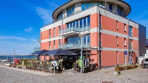 Ein mehrstöckiges Gebäude mit einer abgerundeten Ecke, das Balkone und große Fenster aufweist.