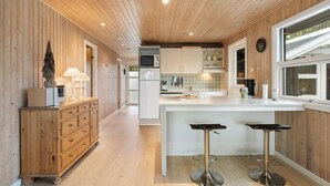 Una cocina moderna con paneles de madera, una isla central con taburetes altos y un microondas.