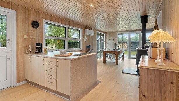 Una cocina moderna con armarios de madera, una isla grande y una zona de comedor con vistas al exterior.
