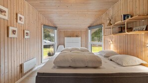 Un dormitorio acogedor con una cama grande, paredes de madera y vistas al exterior.