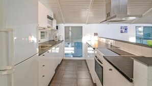 Ett modernt kök med vita skåp, vitvaror i rostfritt stål och ett kaklat golv.