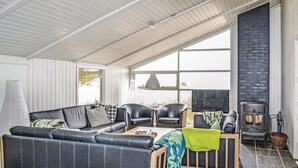 Ett modernt vardagsrum med en hörnsoffa, två fåtöljer, ett soffbord och en öppen spis.