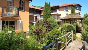 Ein Hotel mit mehreren Balkonen, einer Holzterrasse und üppiger Vegetation.