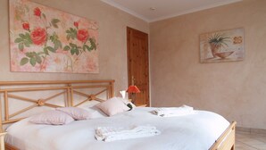 Ein Schlafzimmer mit einem hölzernen Bett, weißer Bettwäsche und zwei Bildern an den Wänden.