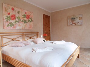 Ein Schlafzimmer mit einem hölzernen Bett, weißer Bettwäsche und zwei Bildern an den Wänden.