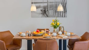Una tavola imbandita per la colazione, con un vaso di fiori e un quadro appeso al muro.