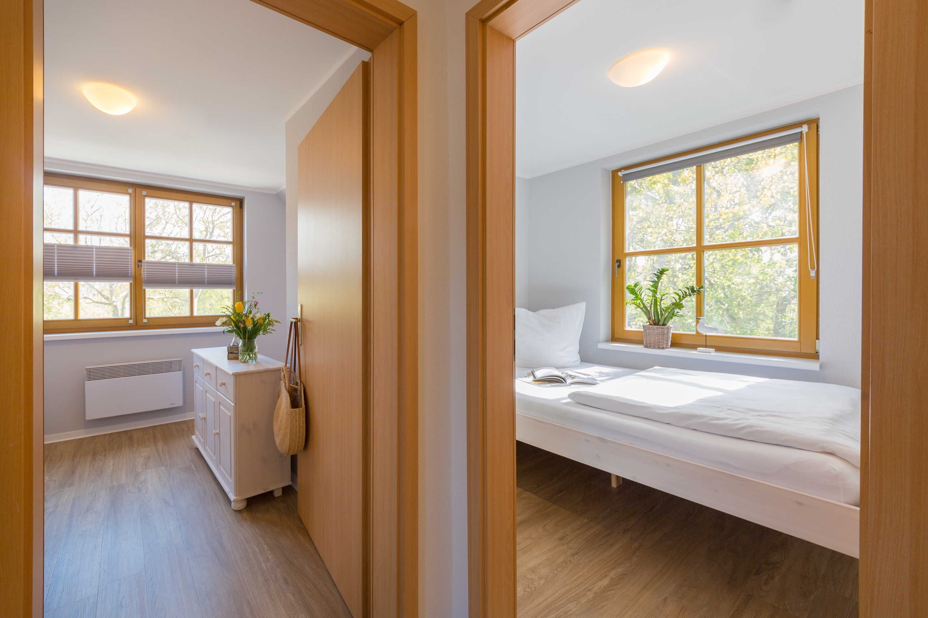 Un dormitorio con cama, ventana con vistas a árboles, mesita de noche y radiador.