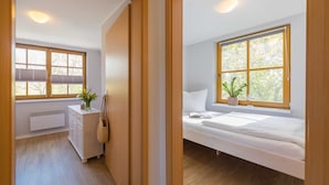Una camera da letto con un letto, una finestra vista alberi, un comodino e un termosifone.