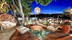 An outdoor seating area with wicker furniture, a round wooden table, and a decorative lantern. - Stunning apartment in Imperia IM (Imperia IM)