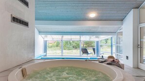 Ett spa-rum med ett bubbelbad, en glasdörr som leder ut och en takfläkt.