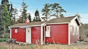 A small red cabin with a white door, a small window, and a chimney.