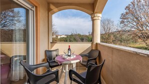 A balcony with a table and chairs, a bottle of wine, and a checkered tablecloth. - 2 bedroom cozy apartment in Medulin (Medulin)