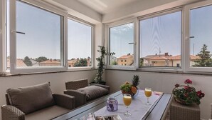 A cozy room with a sofa, a table with drinks and fruit, and large windows offering a view of buildings. - Awesome apartment in Valbandon with WiFi (Valbandon)