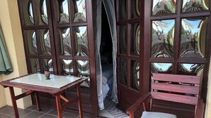A room with a wooden table and bench, a patterned door, and a tiled floor. - Holiday home with barbecue and garden furniture (Siófok)