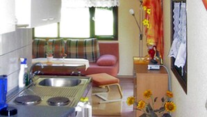A compact kitchen with a sink, stove, and a dining area with a chair and a table.