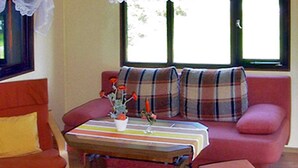 A cozy living room with a plaid sofa, a wooden coffee table with a striped tablecloth, and a small potted plant.