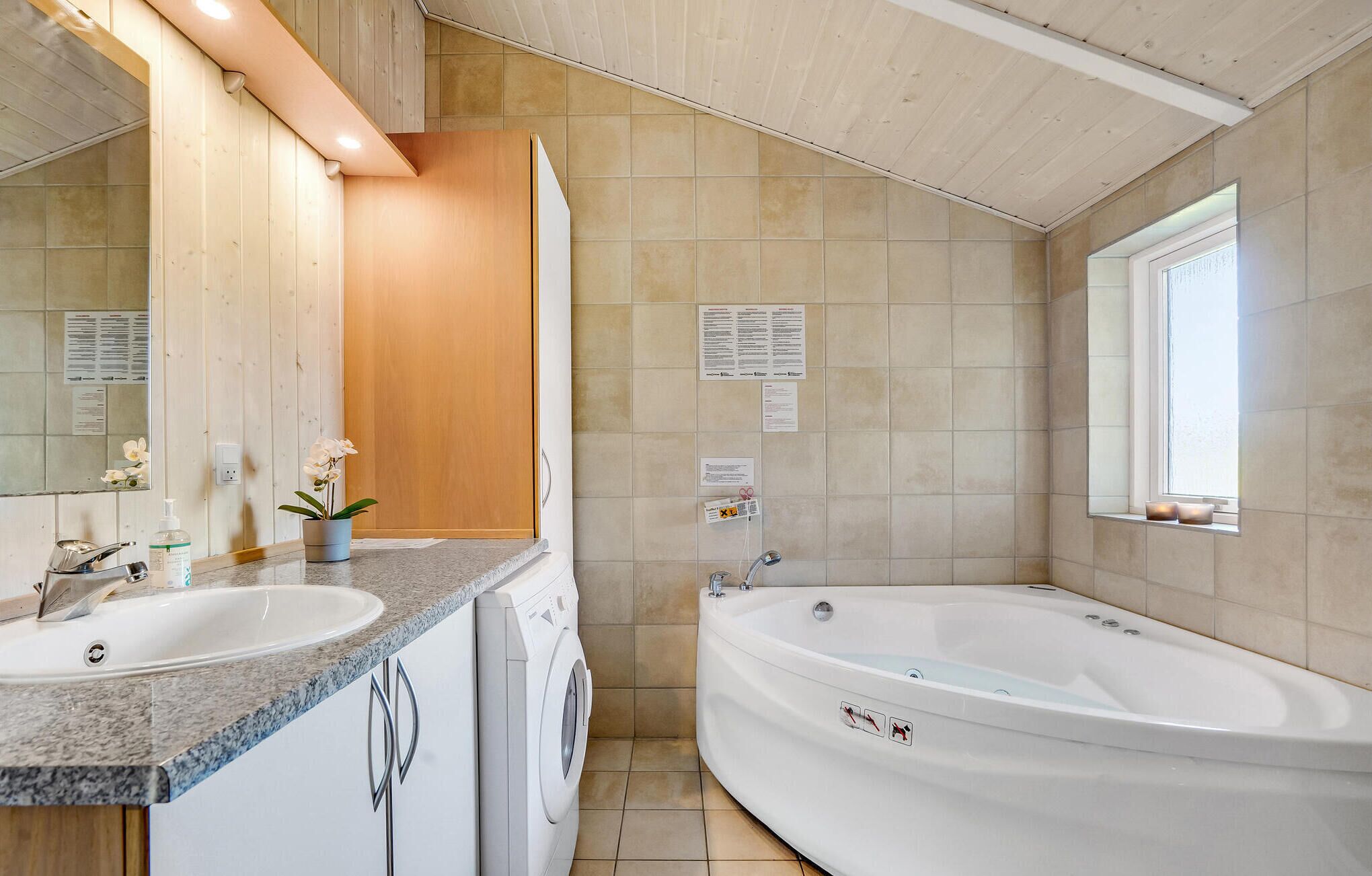Une salle de bain avec deux lavabos, un lave-linge, une baignoire et une fenêtre.