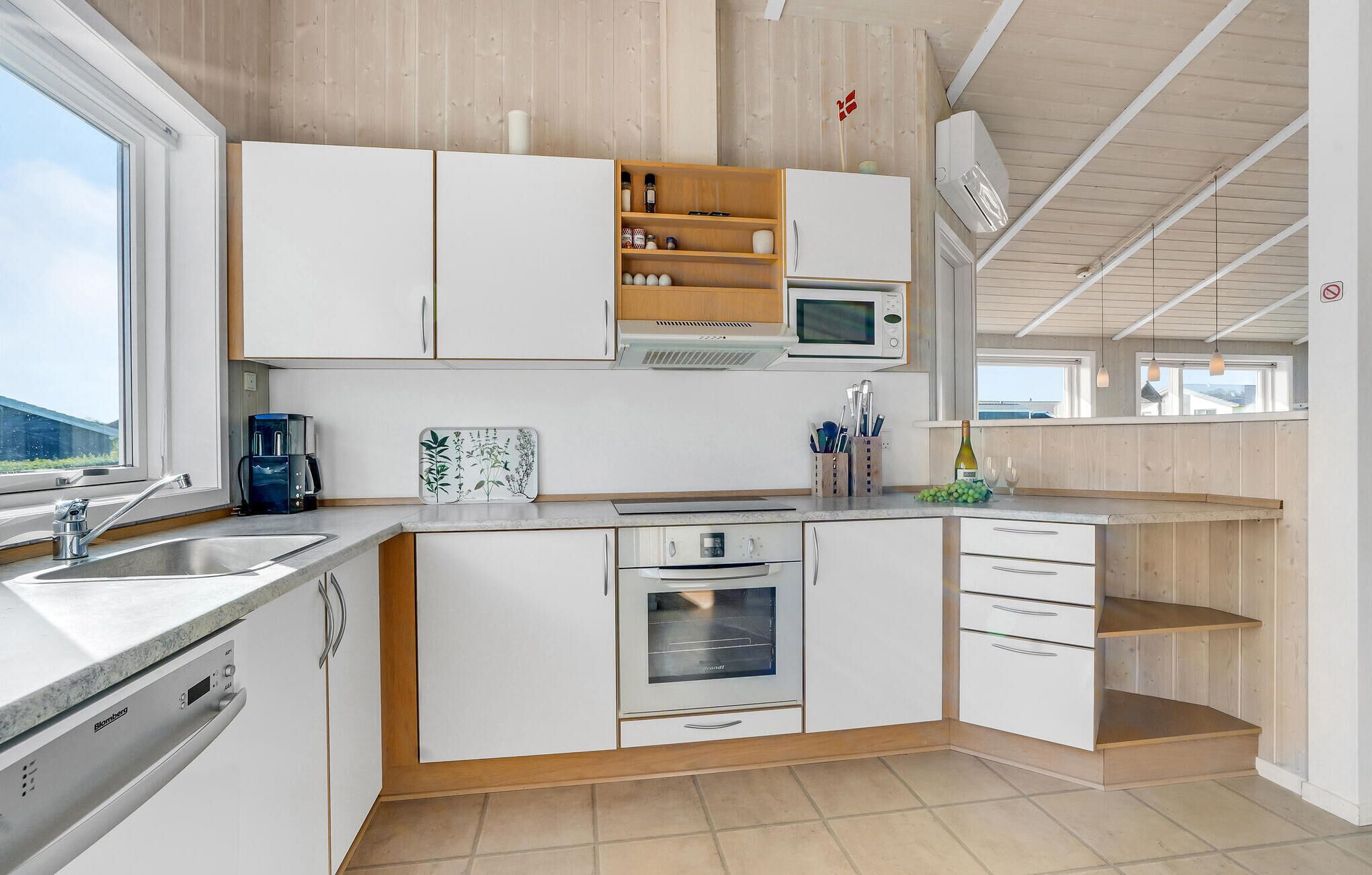 Een moderne keuken met witte kasten, een ingebouwde magnetron en een fornuis.