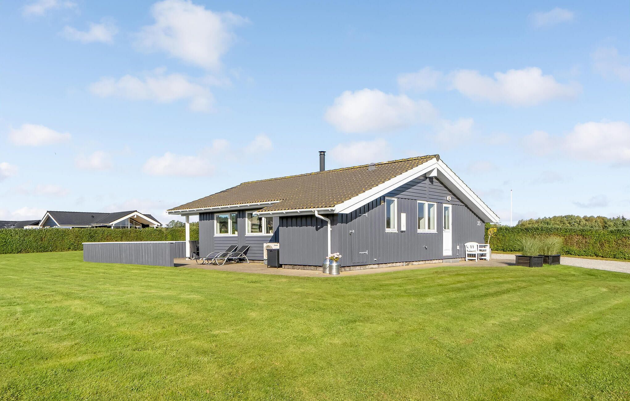 Une maison de plain-pied à l’extérieur gris, avec un toit à deux versants et un petit jardin devant.