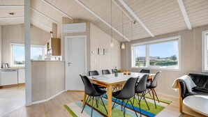 Eine moderne Küche mit weißen Schränken, einem Geschirrspüler und einem Fenster mit Blick auf einen Garten.