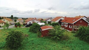 A residential area with houses, a black car, and a body of water in the background.