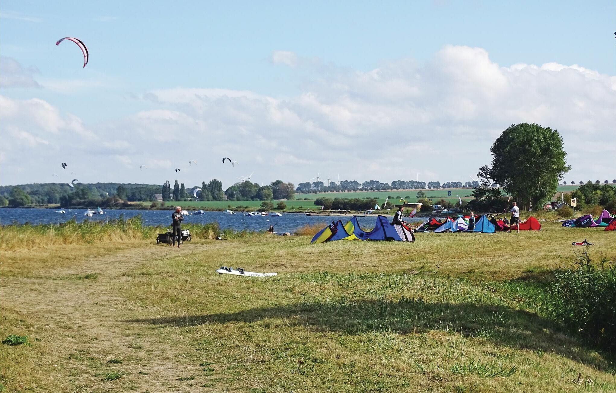 A grassy field with tents and a lake in the background.