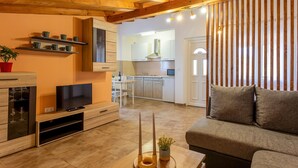 Un salon moderne avec un téléviseur, un canapé et un coin repas à l’arrière-plan.