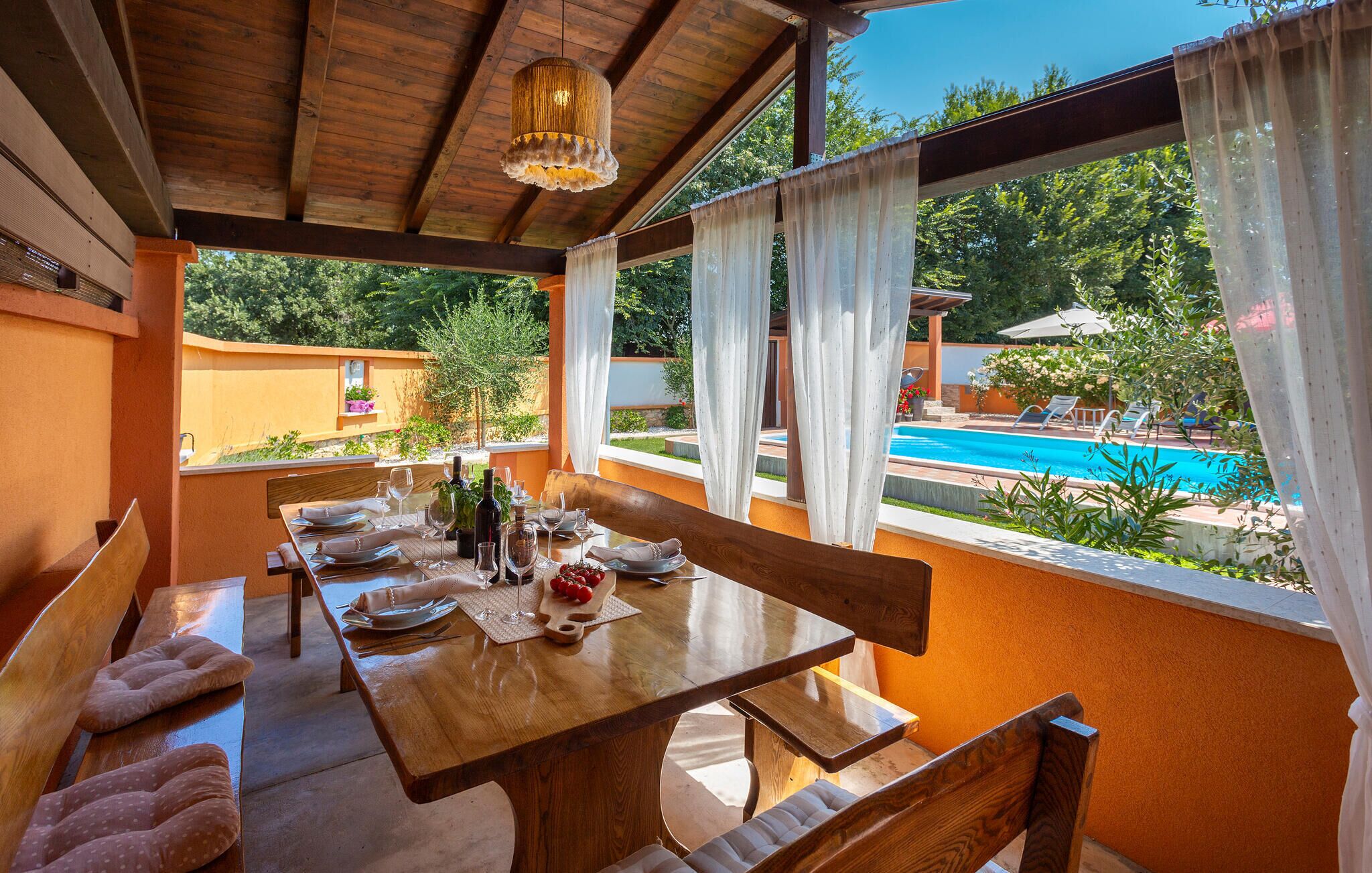 Ein Holzespeisesaal für vier Personen mit Blick auf einen Swimmingpool und Grünflächen.