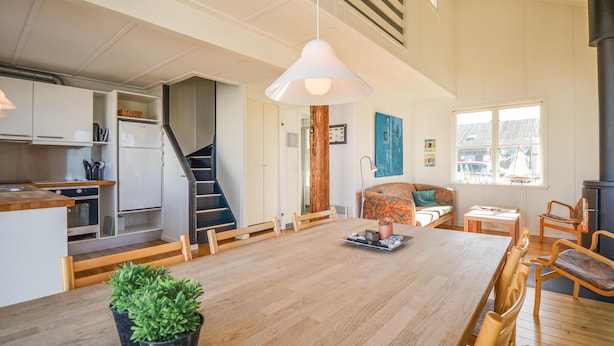 Une cuisine spacieuse avec une table en bois, un coin repas avec des chaises, un escalier et un salon avec un canapé et une fenêtre.
