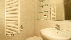 A bathroom with a white toilet, a sink, a mirror, and a towel rack. - Residence Seestern Whg S-13. - See-13 (Kühlungsborn)