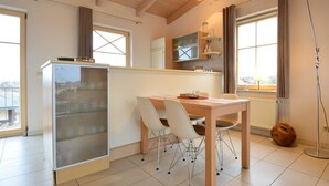 A modern kitchen with a dining area, wooden ceiling, and large windows. - Residence Seestern Whg S-13. - See-13 (Kühlungsborn)
