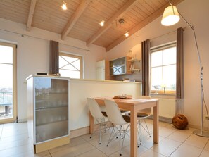 Une cuisine moderne avec un coin repas, un plafond en bois et de grandes fenêtres.