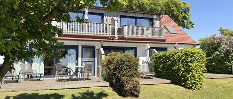 A two-story building with a balcony, outdoor seating area, and a well-maintained lawn.