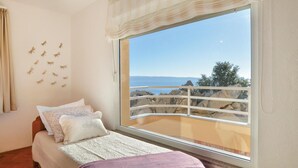 A bedroom with a large window overlooking rocky terrain and a body of water. - Stunning home in Podstrana with sauna (Podstrana)