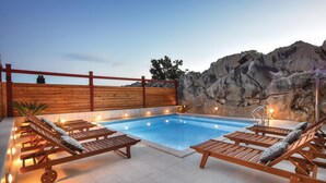 A rooftop pool area with wooden loungers and a stone wall backdrop. - Stunning home in Podstrana with sauna (Podstrana)