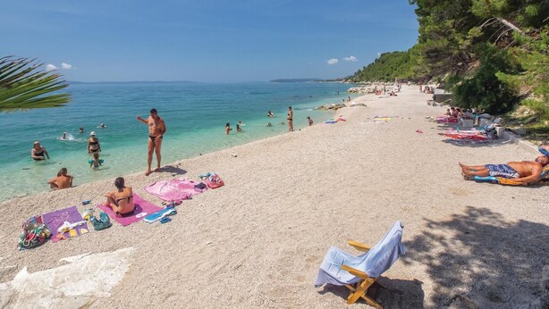 A beach with people sunbathing and swimming, clear blue water, and a sandy shore. - Stunning home in Podstrana with sauna (Podstrana)