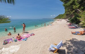A beach with people sunbathing and swimming, clear blue water, and a sandy shore. - Stunning home in Podstrana with sauna (Podstrana)