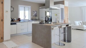 A modern kitchen with a central island, white cabinetry, and stainless steel appliances. - Awesome home in St Nazaire de Ladarez (St Nazaire de Ladarez)