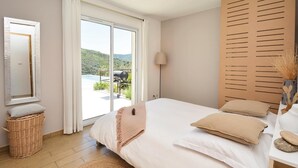 A bedroom with a large bed, a view of a pool and hills, a wicker basket, and a wooden panel wall. - Awesome home in St Nazaire de Ladarez (St Nazaire de Ladarez)