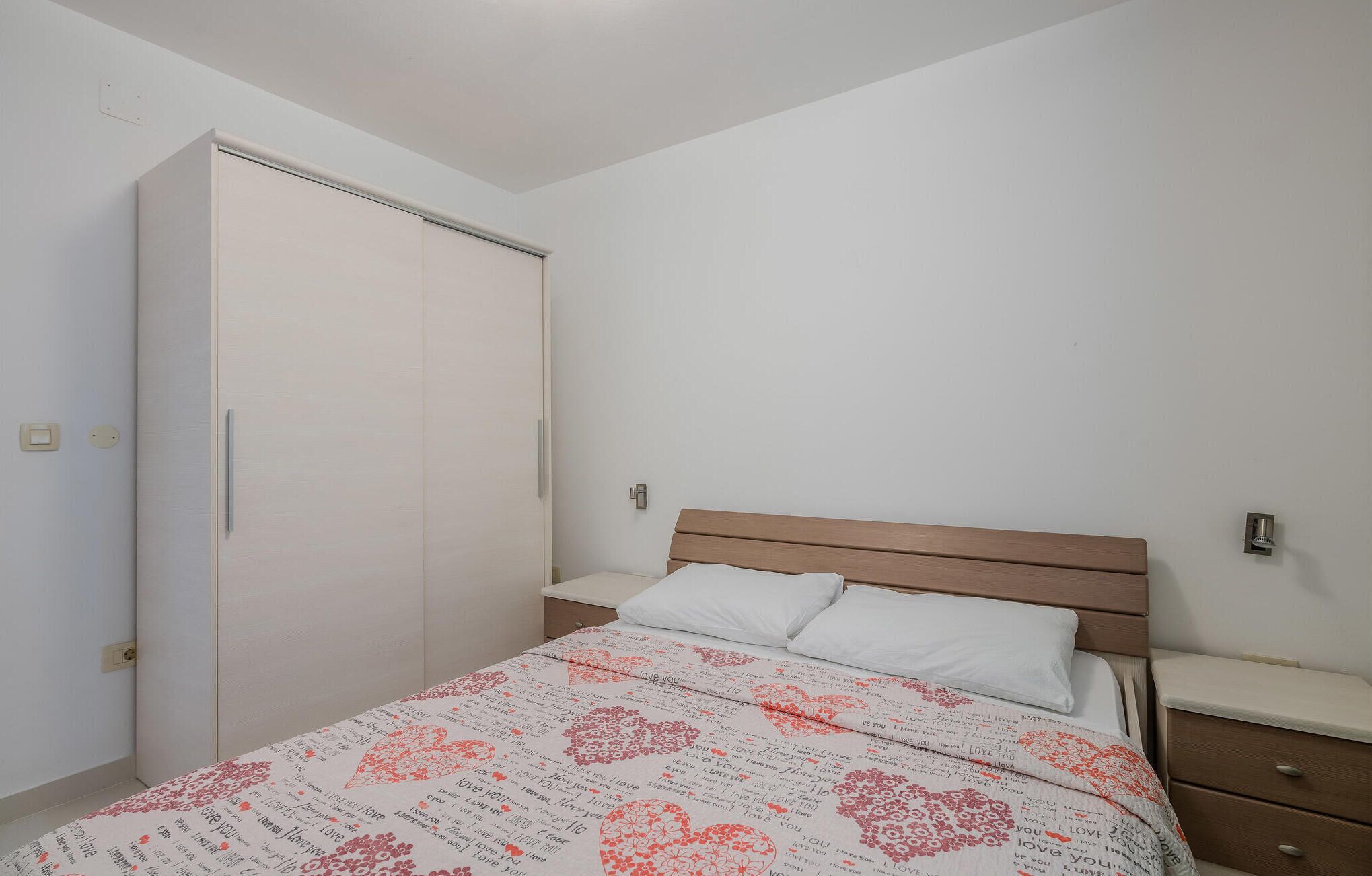 Een slaapkamer met een bed, een houten hoofdbord, een nachtkastje en een kledingkast.