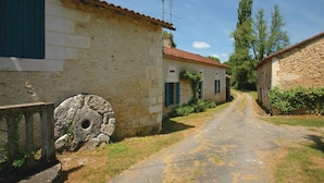 A narrow rural road flanked by stone buildings with traditional architecture, including a well and a stone well cover. - 2 bedroom stunning home in Grignols (Grignols)