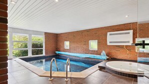 Ein modernes Hallenbad mit Whirlpool, einer Ziegelwand und einem großen Fenster.