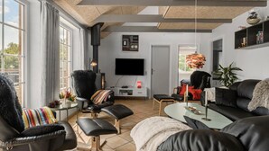 A modern living room with a fireplace, leather furniture, a flat-screen TV, and a large window. - Amazing home in Oksbøl with sauna (Oksbøl)