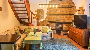 Ein gemütliches Wohnzimmer mit Treppe, Kamin, Fernseher und Essbereich.