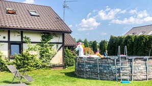 Ein Haus mit einem Steingrundstück, einer weißen Pferdestatue und einem Garten mit zwei Liegestühlen.