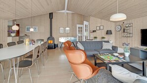 A modern living space with a dining area, a fireplace, a sofa, and a television. - Beautiful home in Væggerløse with sauna (Væggerløse)