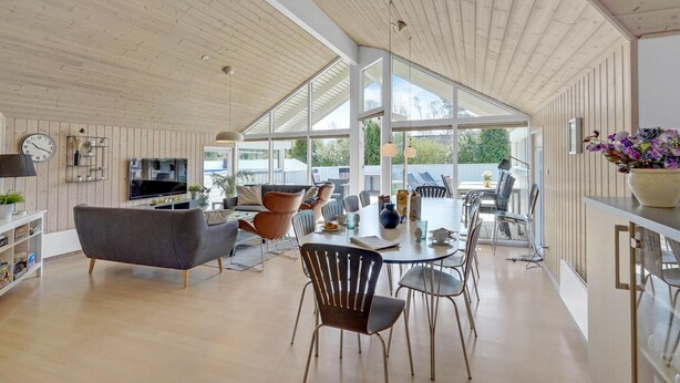 A spacious living area with a high ceiling, a dining table, and modern furniture. - Beautiful home in Væggerløse with sauna (Væggerløse)