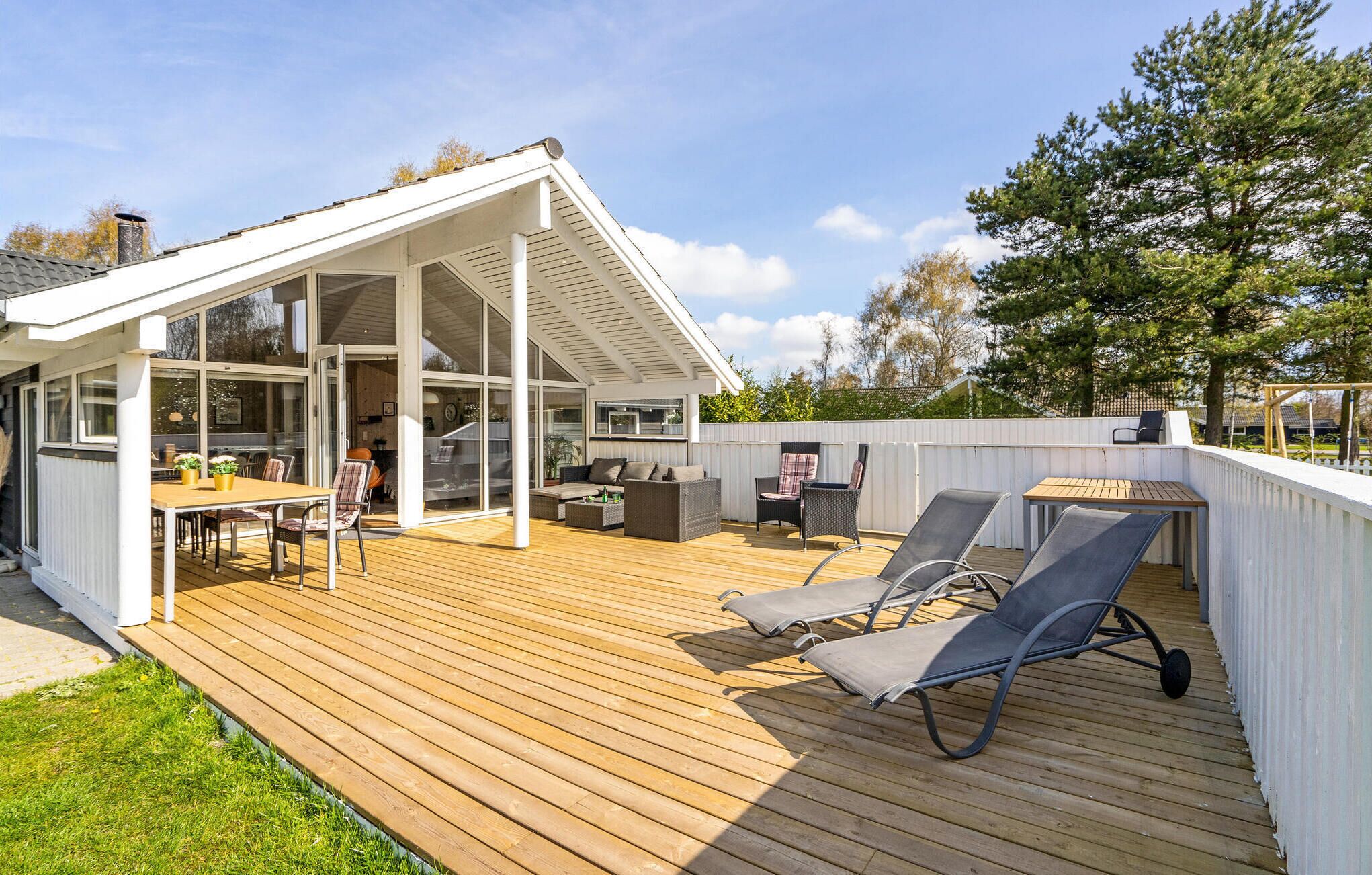 A spacious deck with a dining area, lounge chairs, and a covered patio.
