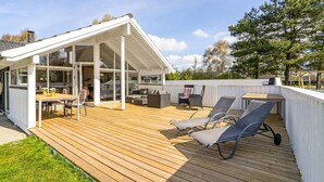 A spacious deck with a dining area, lounge chairs, and a covered patio. - Beautiful home in Væggerløse with sauna (Væggerløse)