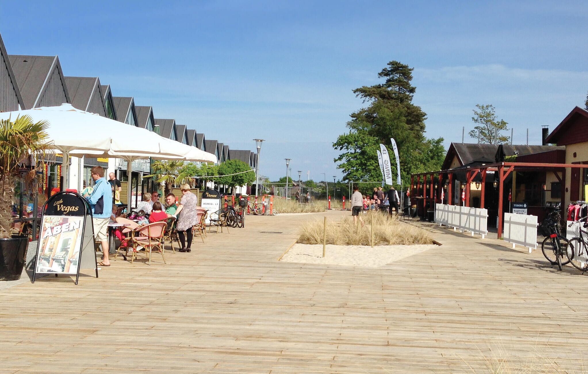 A boardwalk with outdoor seating, a sign for 'ABEN', and a 'WIMBLEDON' banner.